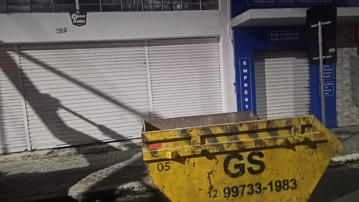 Caçamba amarela da GS estacionada em frente a imóvel com portão de garagem