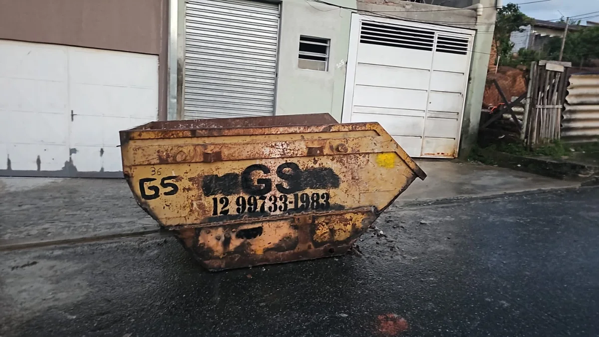 Caçamba amarela da GS diante de portão branco de uma residência