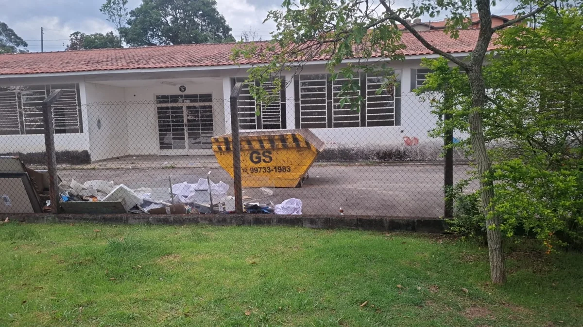 Caçamba amarela da GS em frente a um prédio térreo com jardim