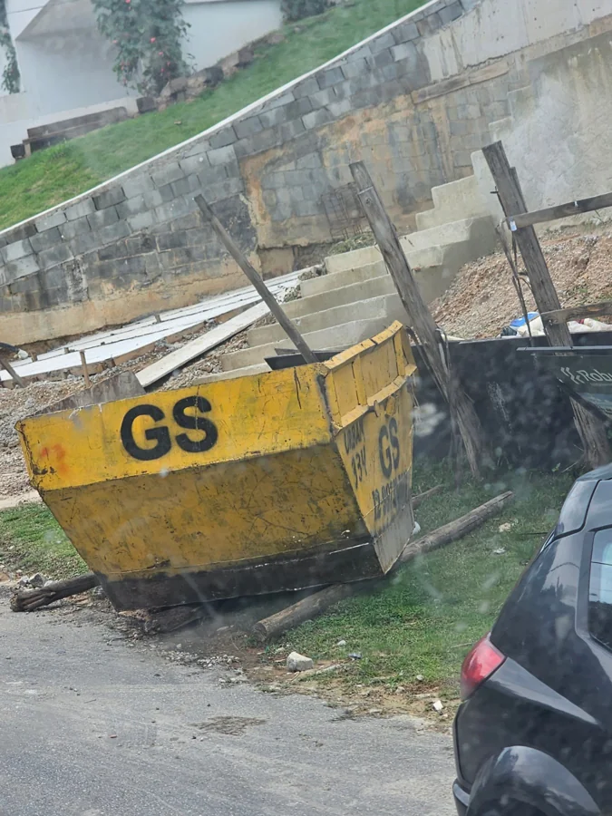 Caçamba amarela da GS junto a uma obra residencial