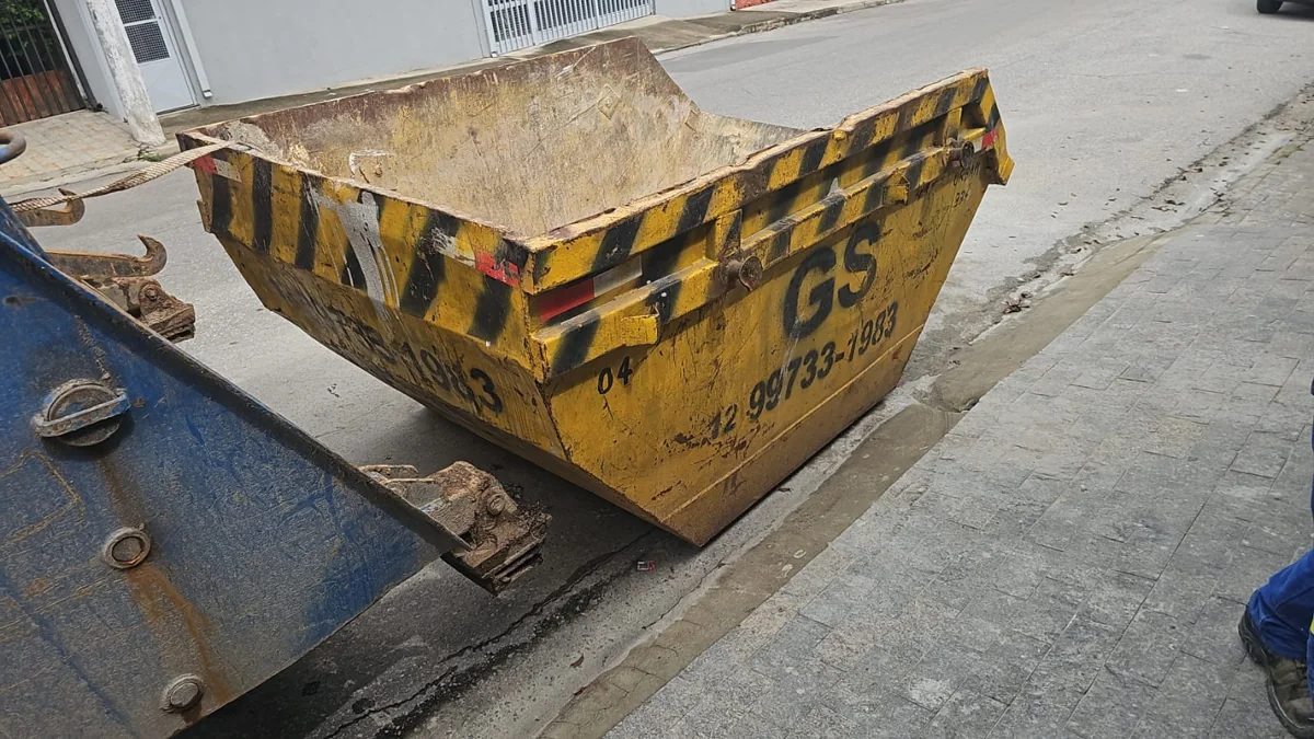 Vista de uma caçamba amarela da GS junto a caminhão poliguindaste